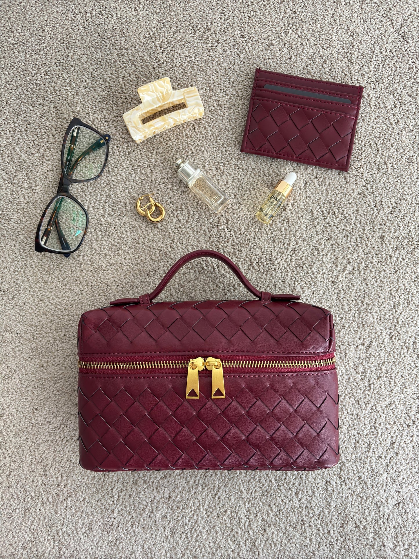 Detailansicht der Juliette Polierte Strukturierte Woven Handtasche aus veganem Leder von Fadenburg, die glänzende goldfarbene Beschläge zeigt.